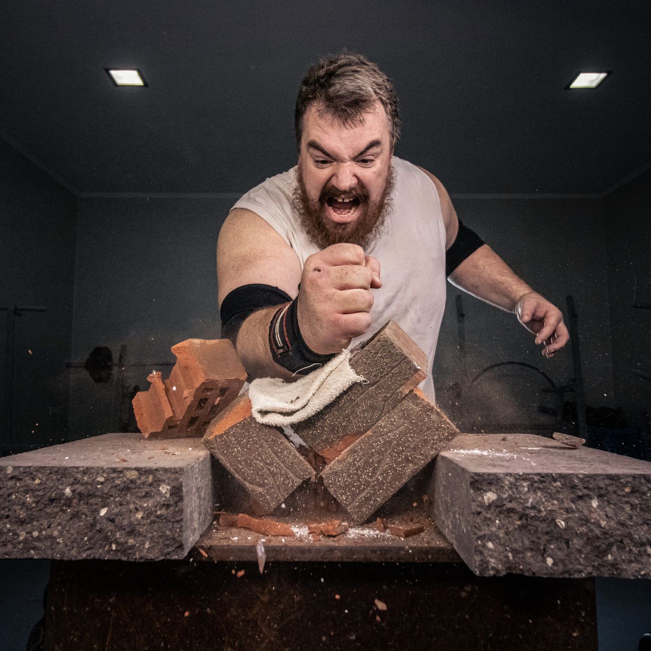 a man breaking bricks over a stone