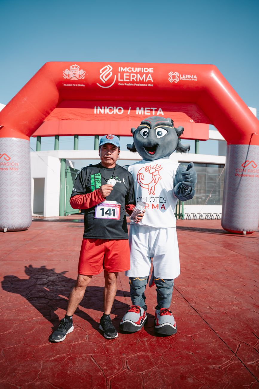 sportsman posing with mascot on finish line