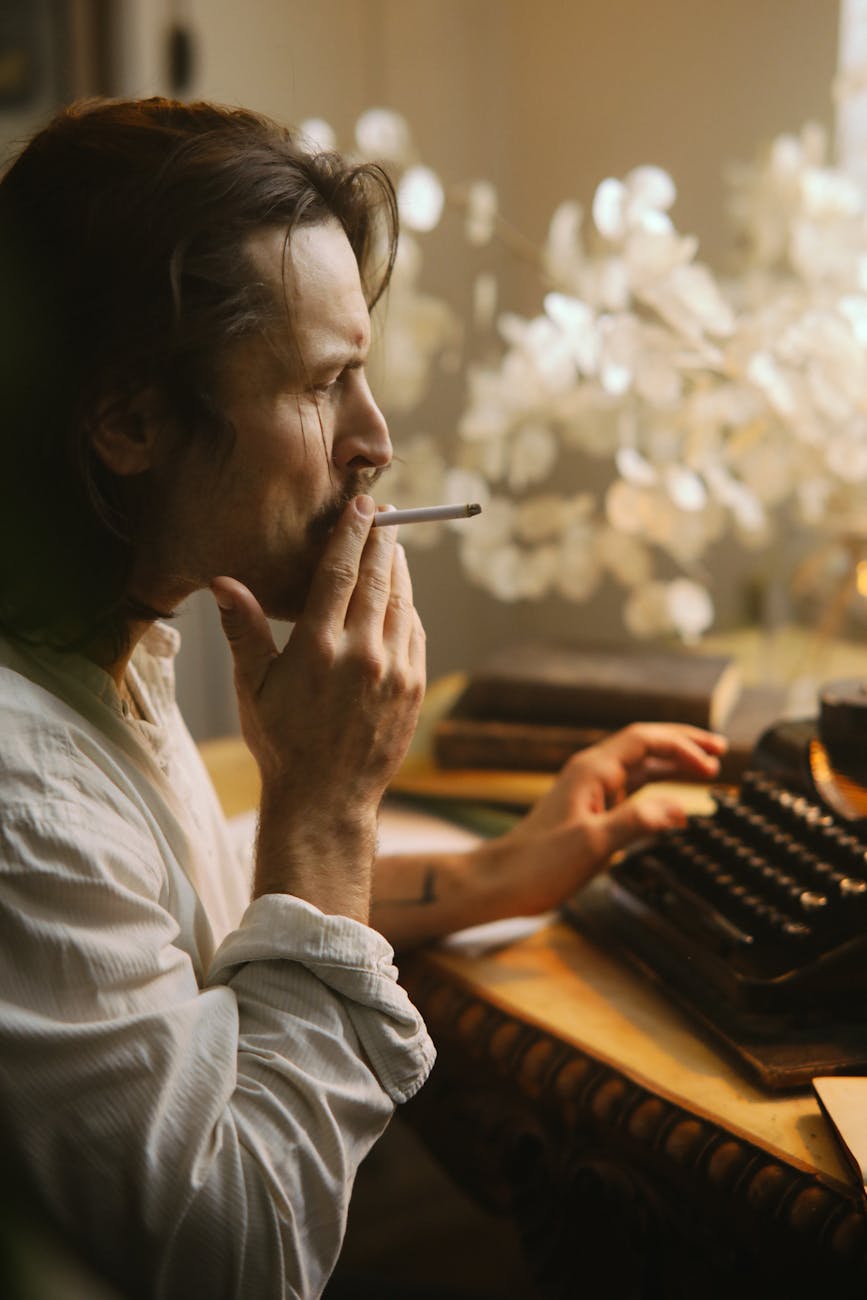 man sitting in front of a typewriter smoking