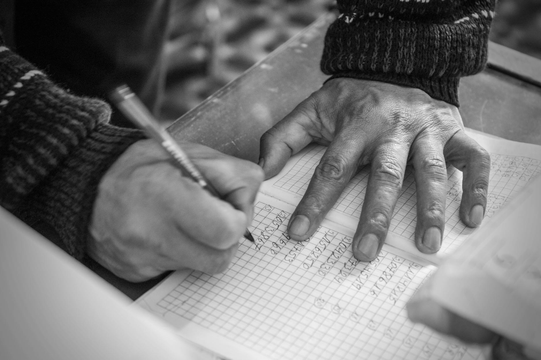 a person writing on white paper