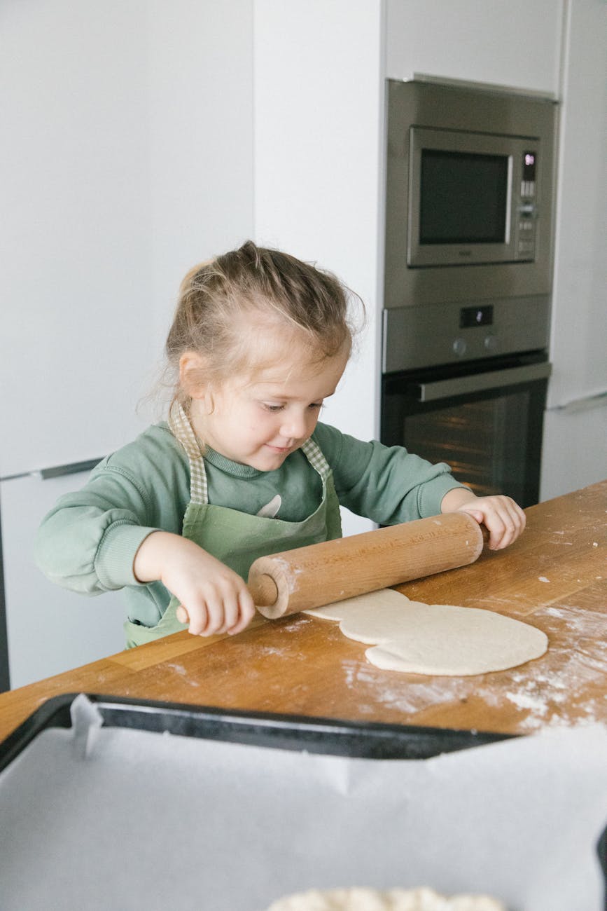 girl in green sweater holding rolling pin