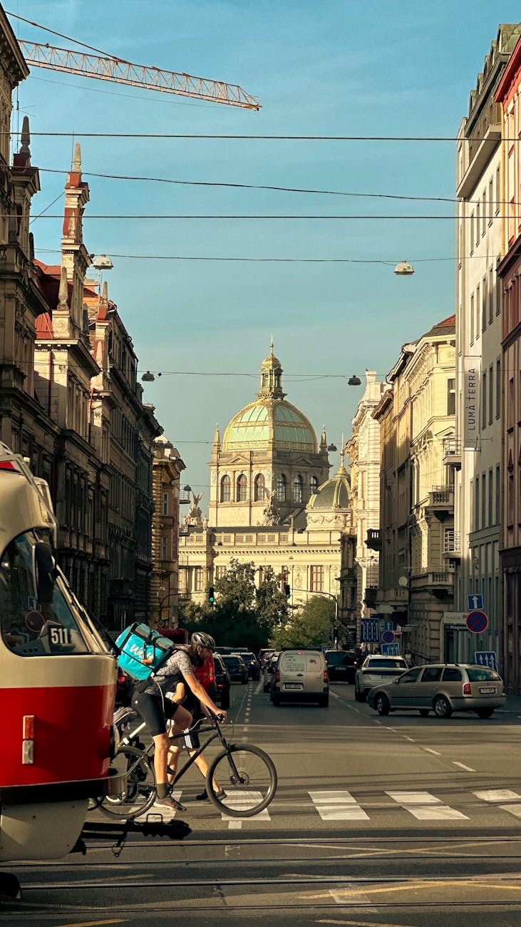 a tram and cyclist on a street with view of the national museum in prague czech republic