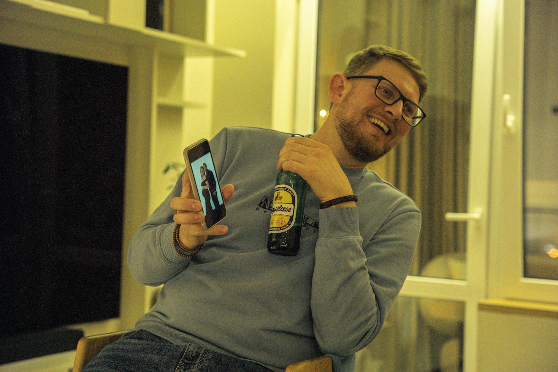 man relaxing at home with beer and smartphone