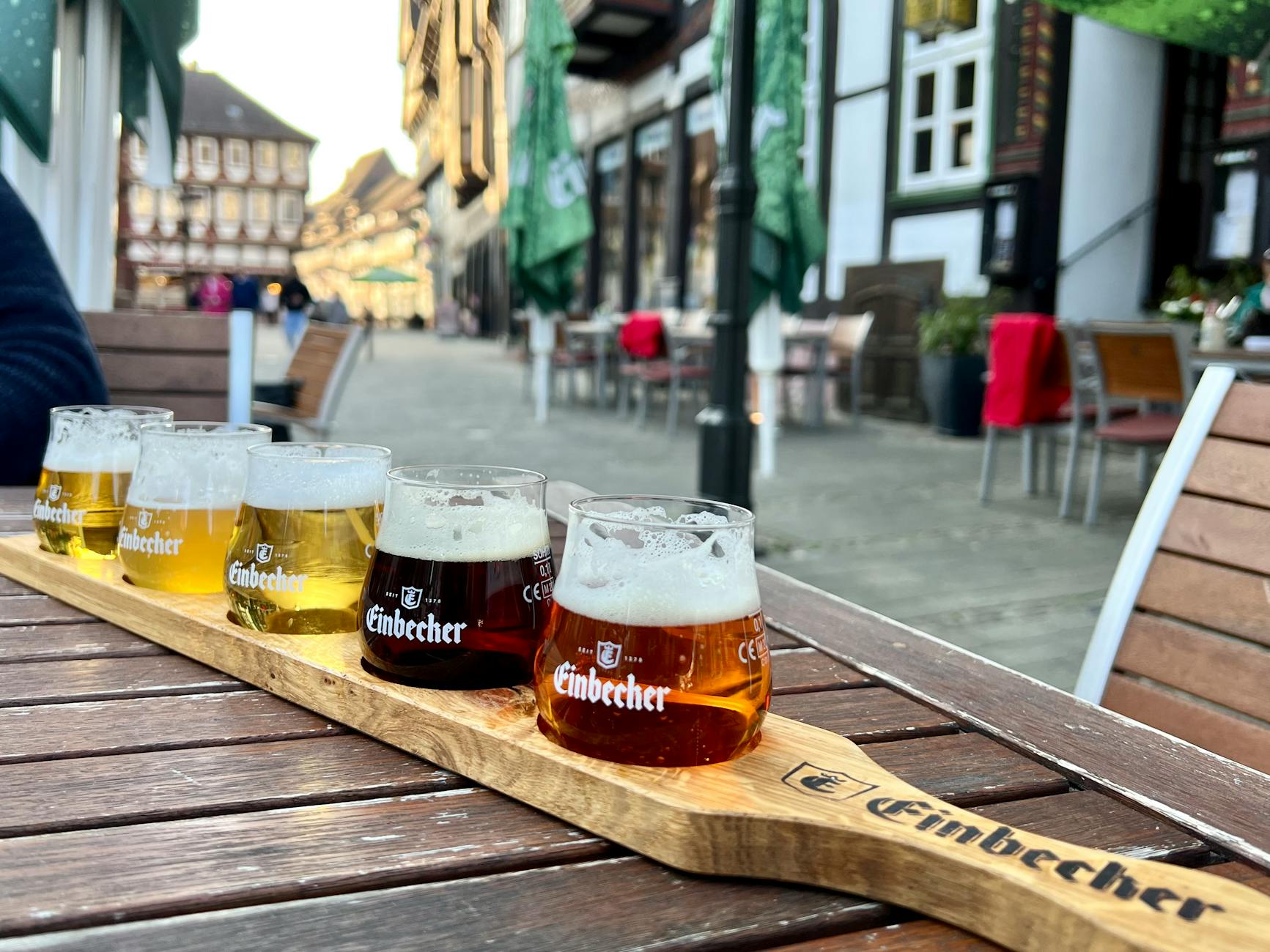 different kinds of beer standing on a wooden tray on a table in brodhaus einbeck restaurant patio