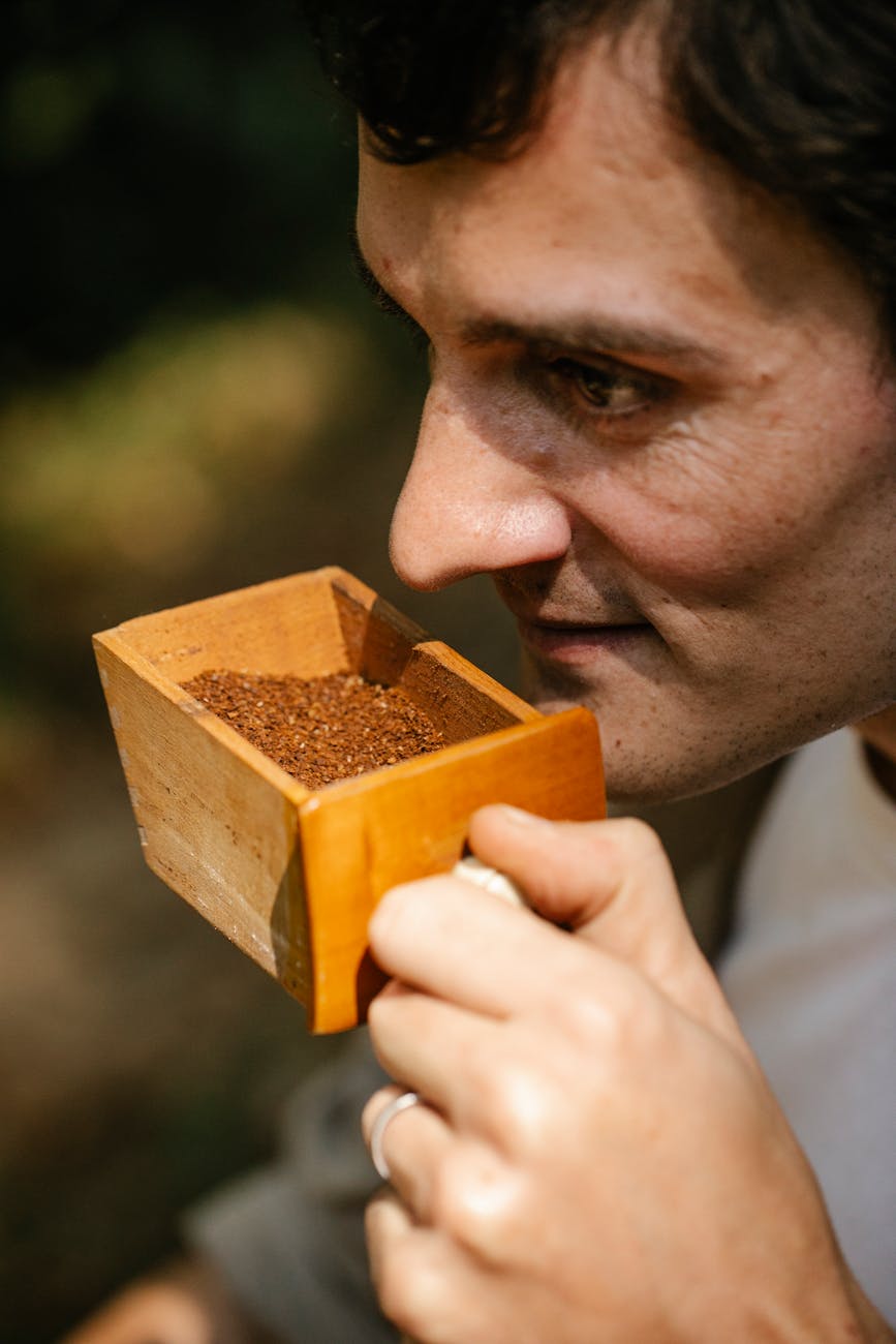 crop man smelling ground coffee in box outdoors