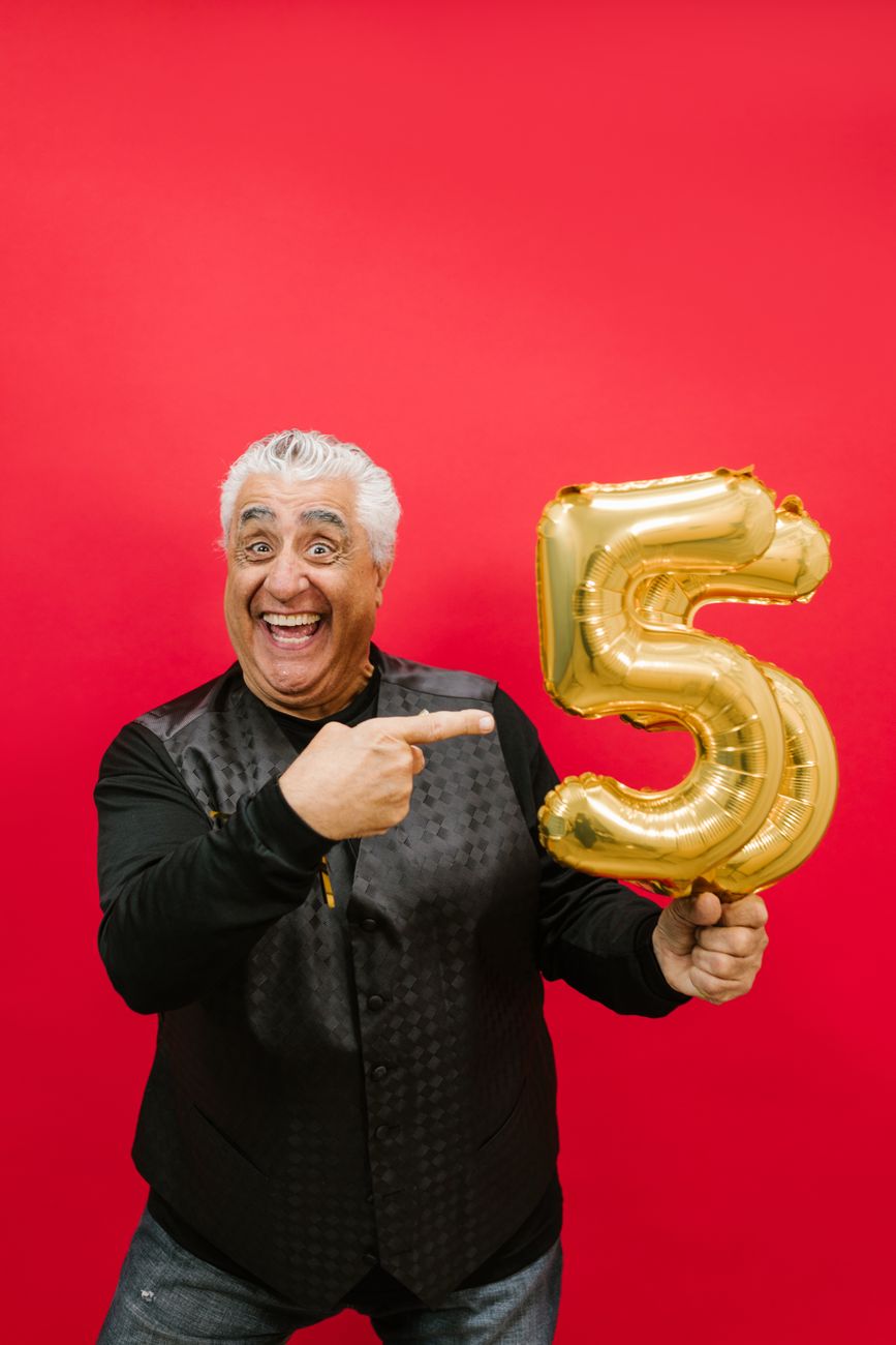 man in black long sleeves holding gold balloons